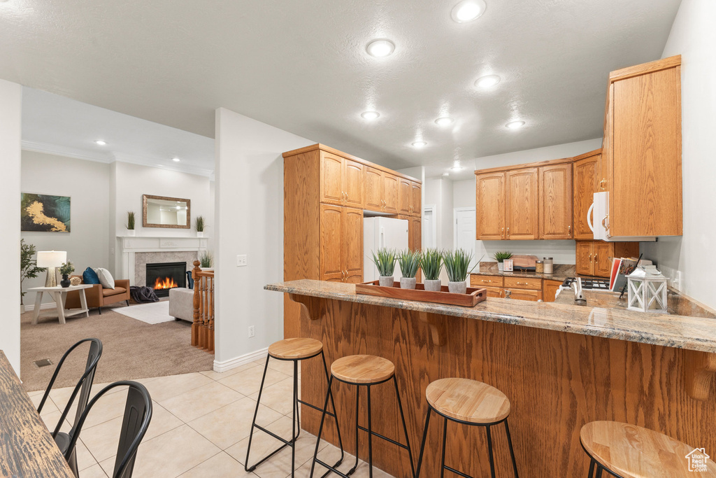 Kitchen with a peninsula, white appliances, light carpet, recessed lighting, and light tile patterned floors