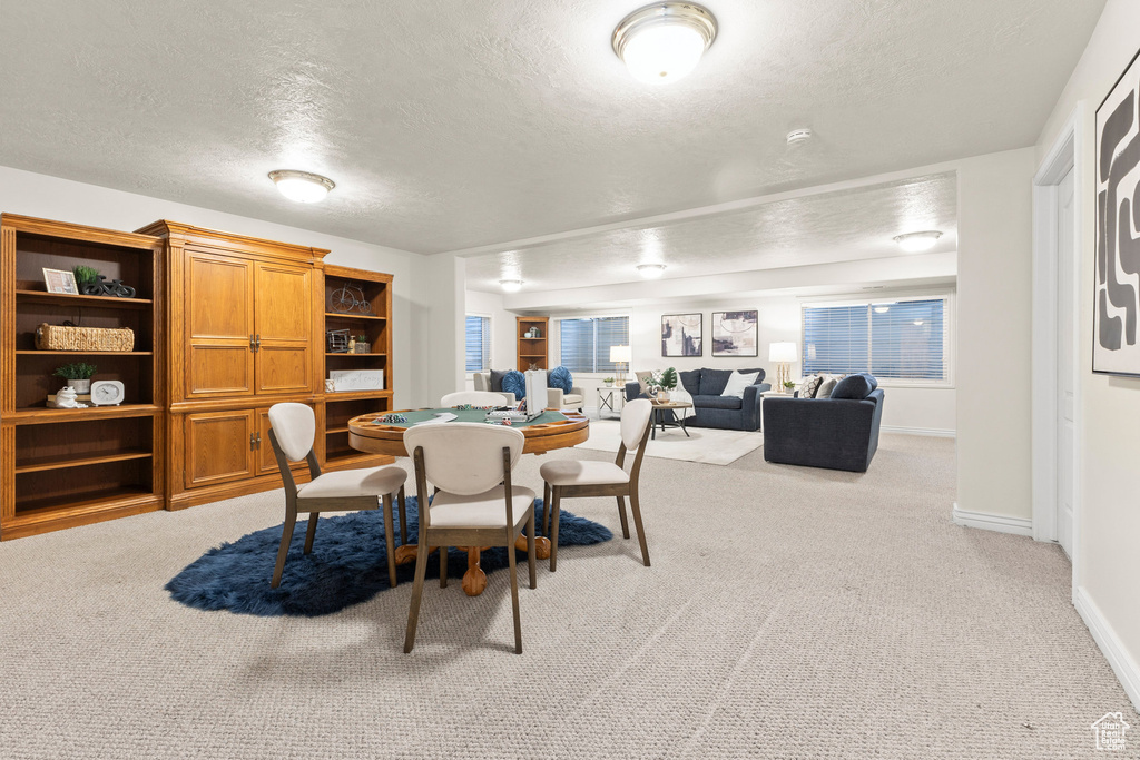 Dining space with a textured ceiling and light colored carpet