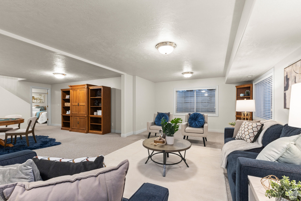 Living area featuring light carpet and a textured ceiling
