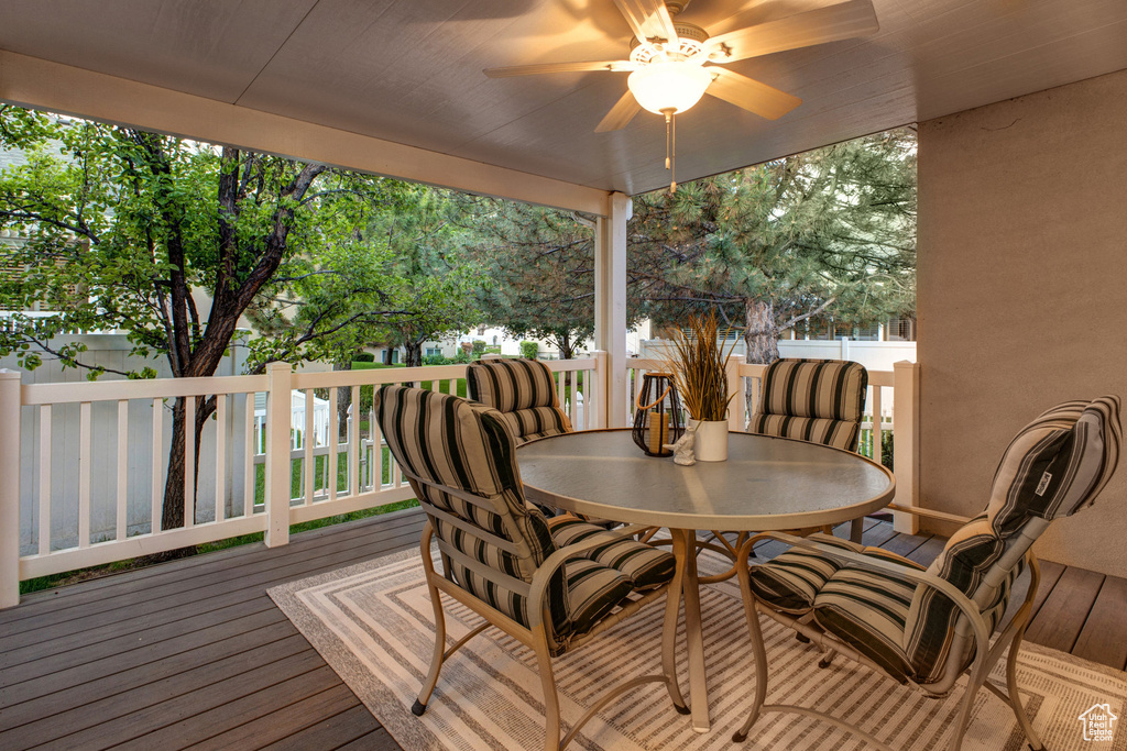 Wooden deck featuring outdoor dining area and a ceiling fan