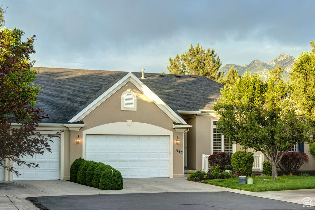 Traditional-style house with stucco siding, a shingled roof, a garage, and a mountain view