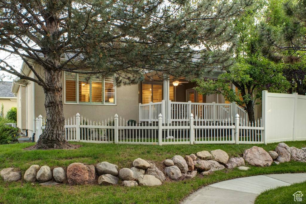View of front of house featuring stucco siding, covered porch, and a fenced front yard