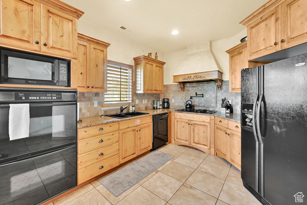 Kitchen featuring black appliances, custom exhaust hood, light brown cabinets, backsplash, and recessed lighting