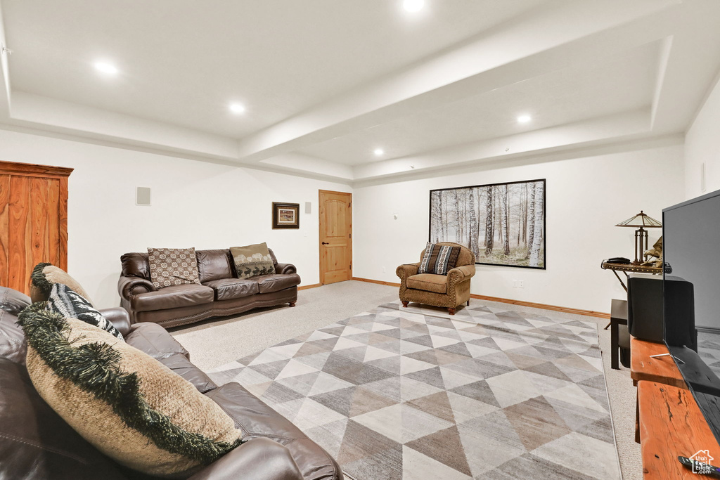 Living area with a raised ceiling, light colored carpet, and recessed lighting