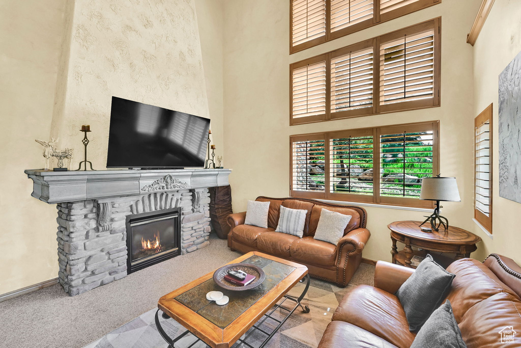 Living area featuring carpet flooring, a fireplace, and a high ceiling
