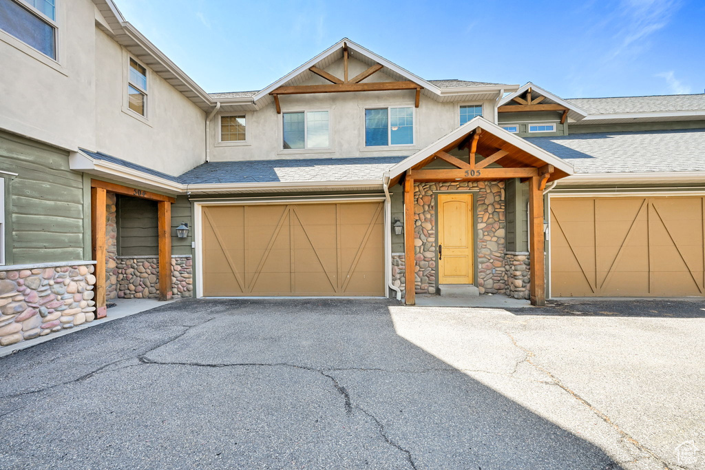 View of front of home featuring stone siding, stucco siding, a garage, and driveway