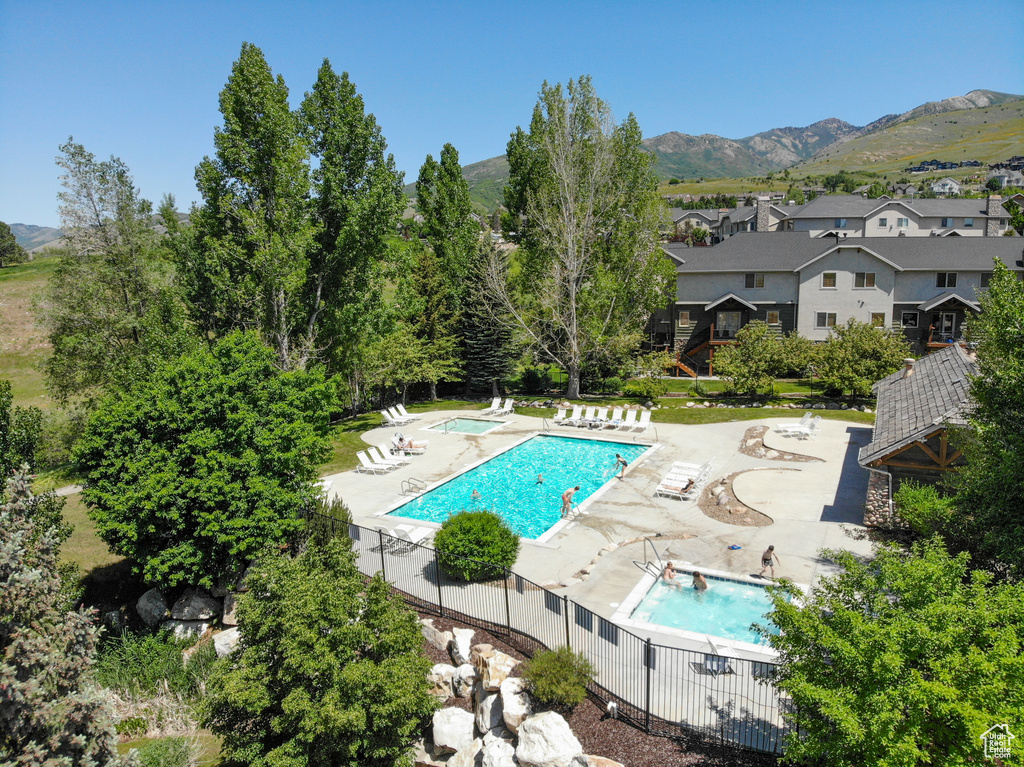 Community pool featuring a community hot tub, a patio area, a mountain view, and a residential view