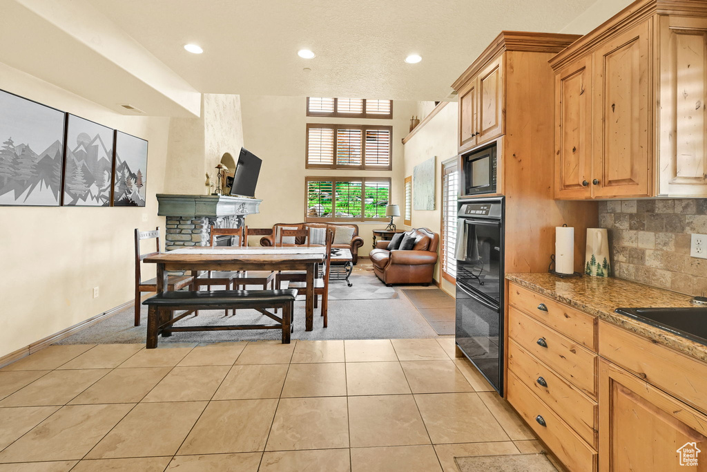 Kitchen featuring black appliances, light tile patterned floors, recessed lighting, stone countertops, and open floor plan