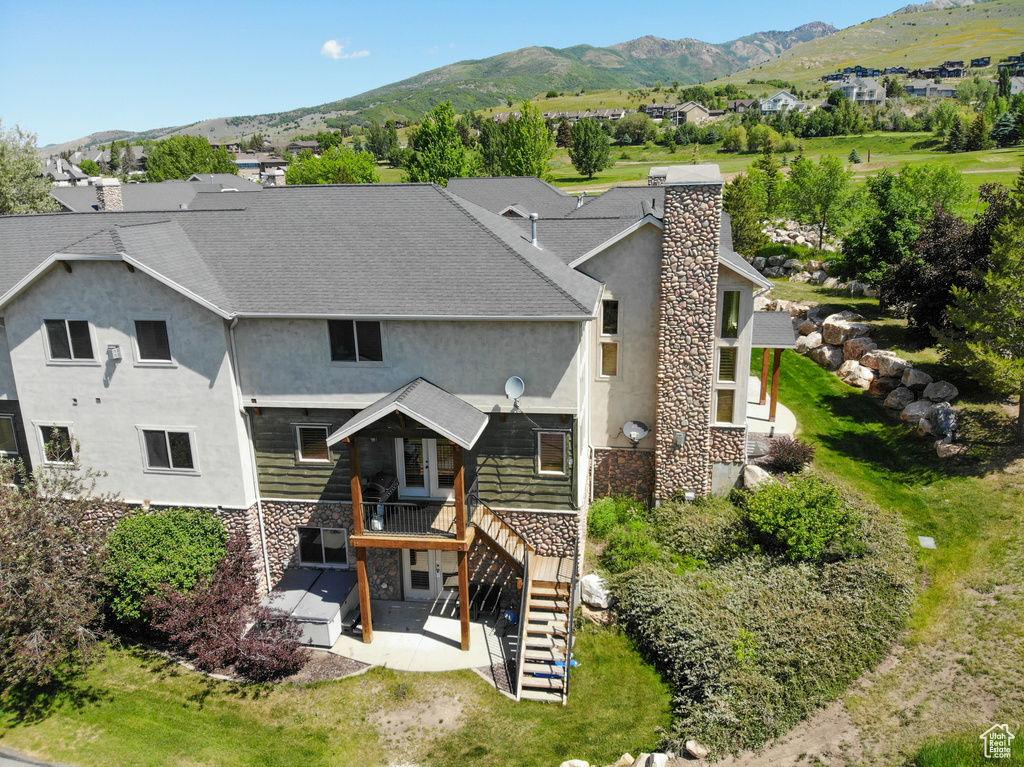 Back of property with stucco siding, stairway, a patio, a deck with mountain view, and stone siding