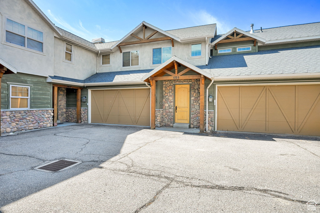 View of front of house featuring stone siding, stucco siding, an attached garage, and driveway