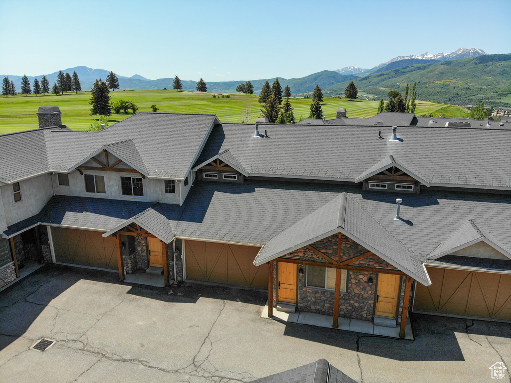 View of front facade with stone siding, a mountain view, driveway, and a porch