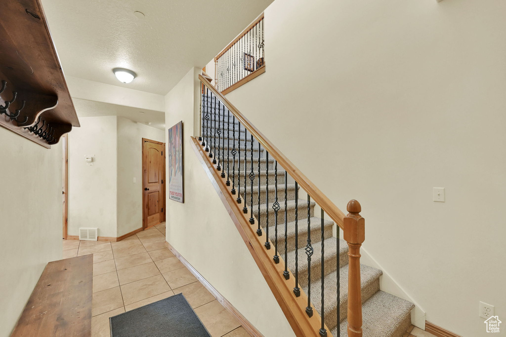 Stairs with tile patterned floors and a textured ceiling