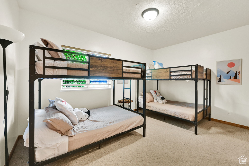 Carpeted bedroom featuring a textured ceiling and baseboards
