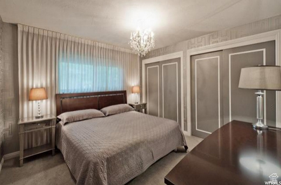 Bedroom with carpet, a chandelier, and two closets
