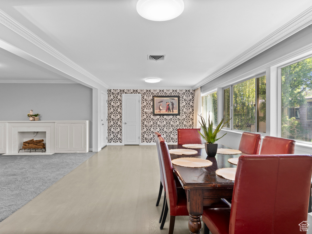Dining area with wallpapered walls and ornamental molding