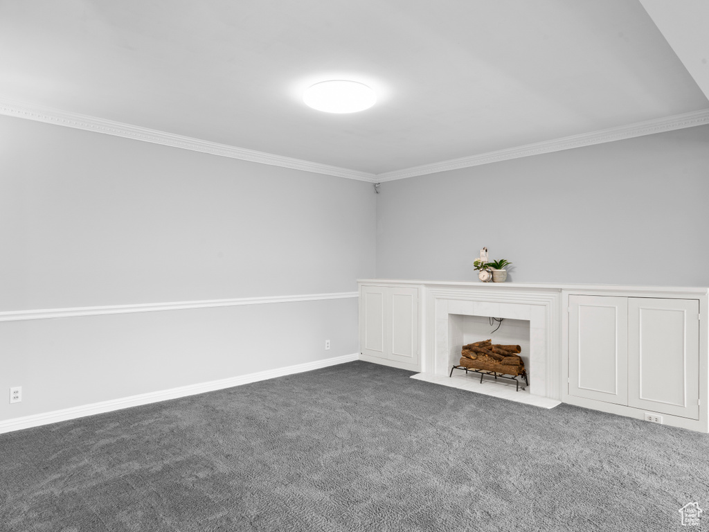 Unfurnished living room with crown molding and dark colored carpet