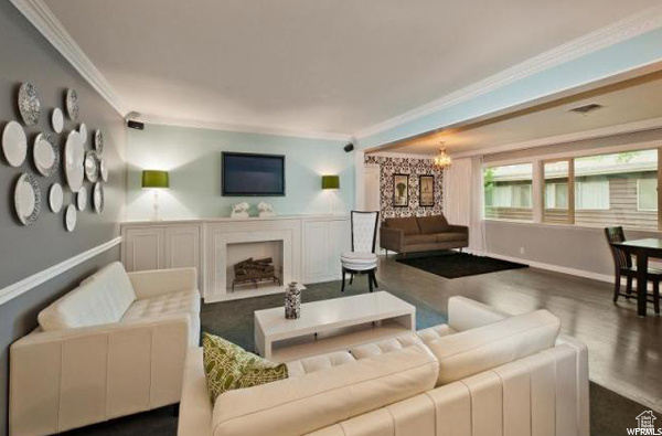 Living area with ornamental molding, wood finished floors, a chandelier, and a fireplace
