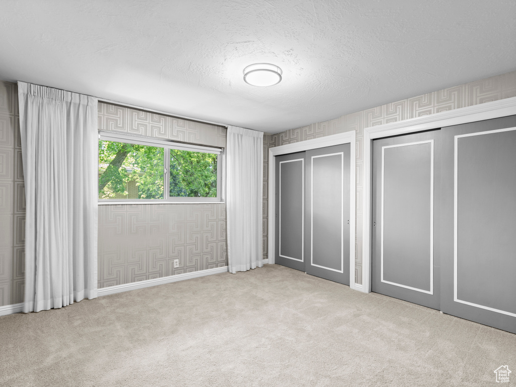 Unfurnished bedroom with multiple closets, carpet flooring, and a textured ceiling