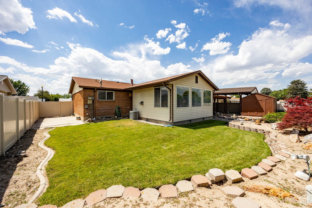 Rear view of house featuring a shed, a fenced backyard, and a patio