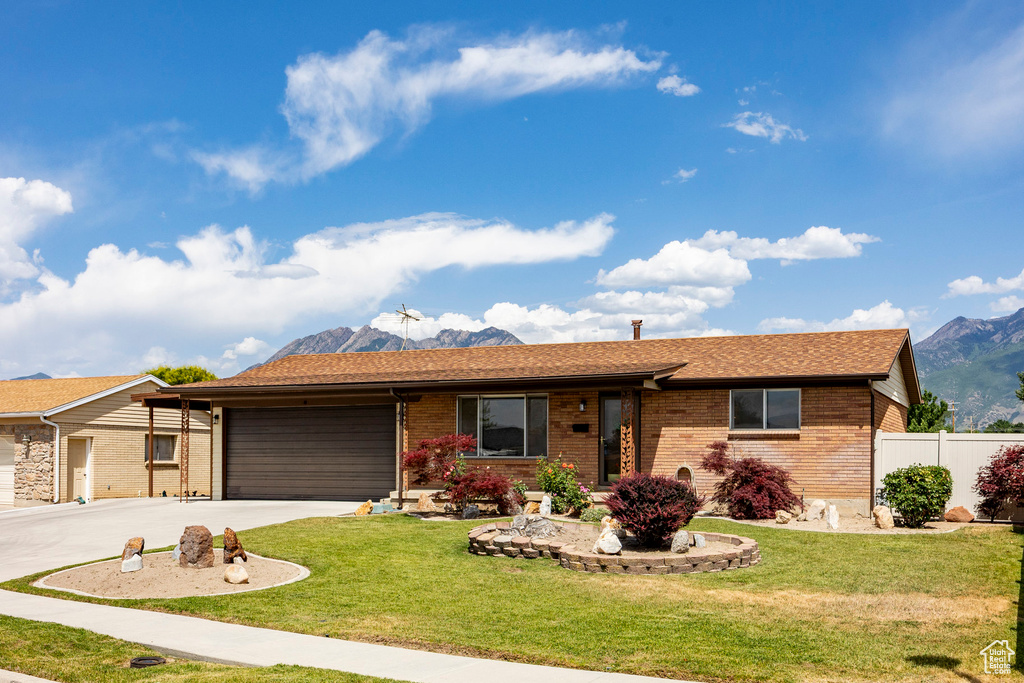 Ranch-style home featuring an attached garage, brick siding, a mountain view, concrete driveway, and roof with shingles