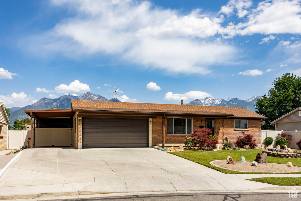 Ranch-style home featuring a mountain view, driveway, an attached garage, and brick siding