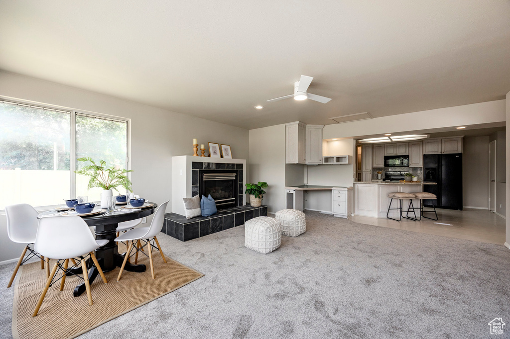 Living area featuring a tiled fireplace, recessed lighting, and light colored carpet