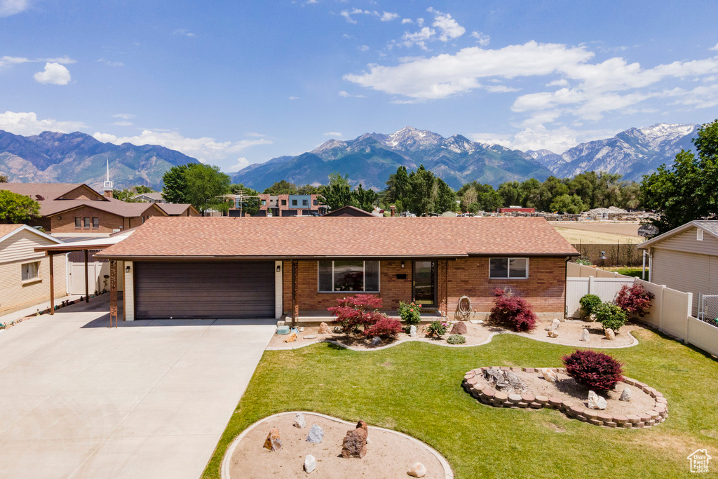 Ranch-style house featuring an attached garage, a mountain view, brick siding, and concrete driveway