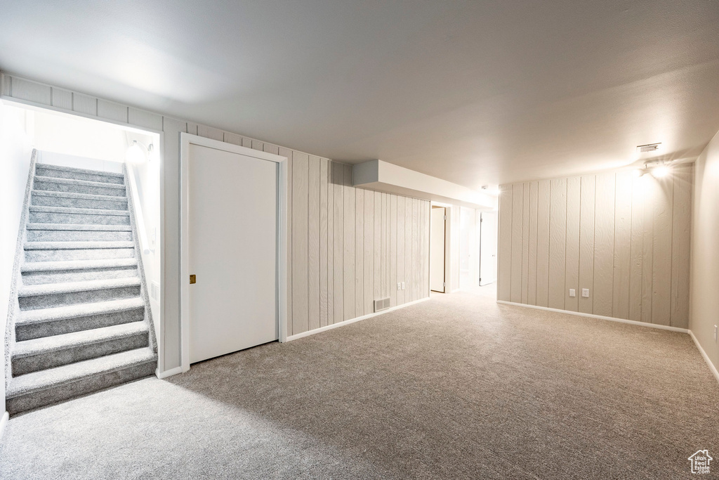Carpeted spare room with stairway and wooden walls
