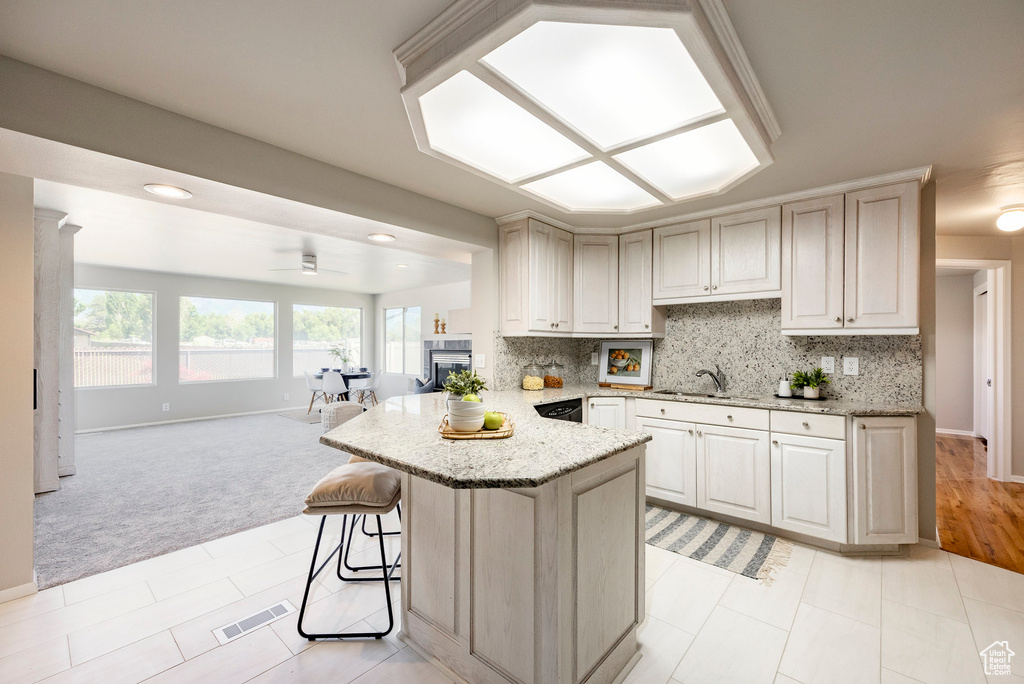 Kitchen with open floor plan, light carpet, a peninsula, and light stone counters
