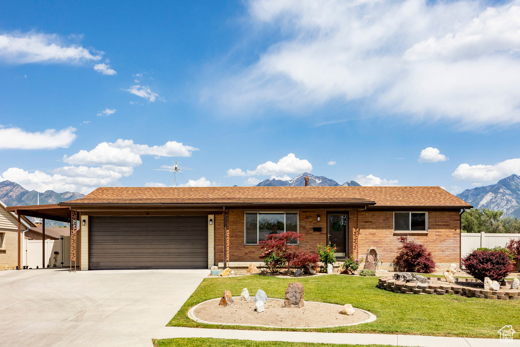 Single story home with a mountain view, a garage, driveway, and brick siding