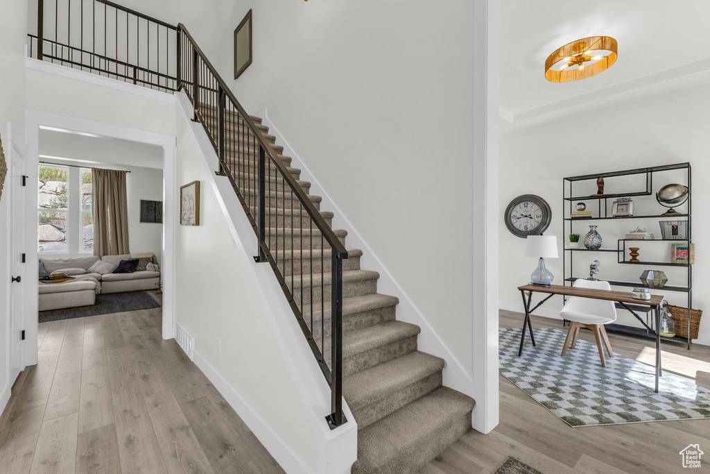 Staircase featuring a towering ceiling and wood finished floors