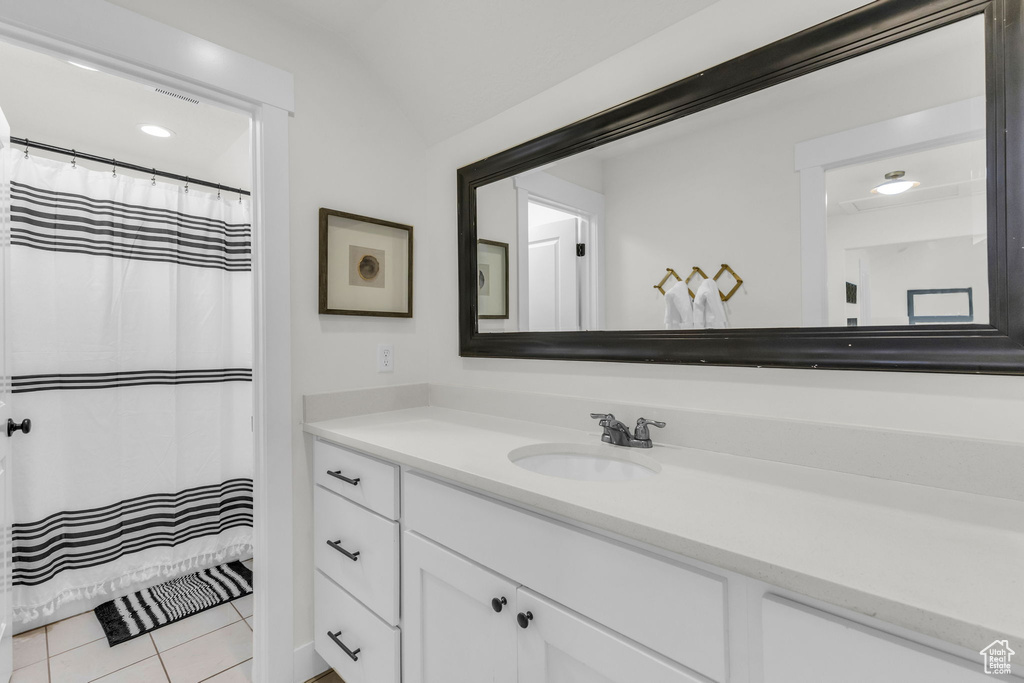 Bathroom with vanity, tile patterned flooring, and lofted ceiling