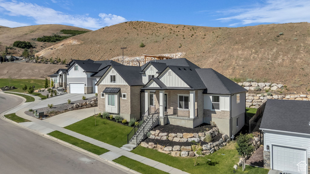 Modern farmhouse style home with driveway, board and batten siding, a mountain view, and a front yard