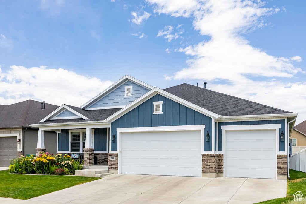 Craftsman-style house featuring a garage, board and batten siding, concrete driveway, and brick siding