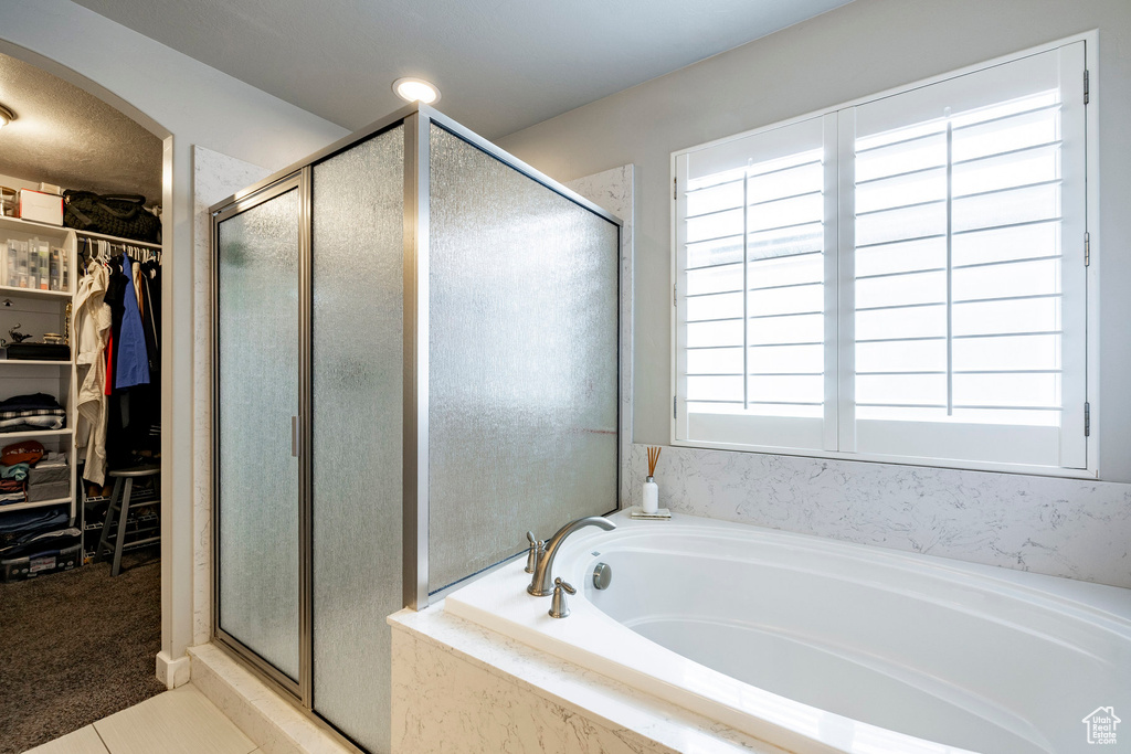 Full bathroom featuring a stall shower, a bath, healthy amount of natural light, and a walk in closet