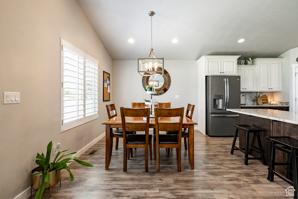Dining room with a chandelier, wood finished floors, recessed lighting, and lofted ceiling