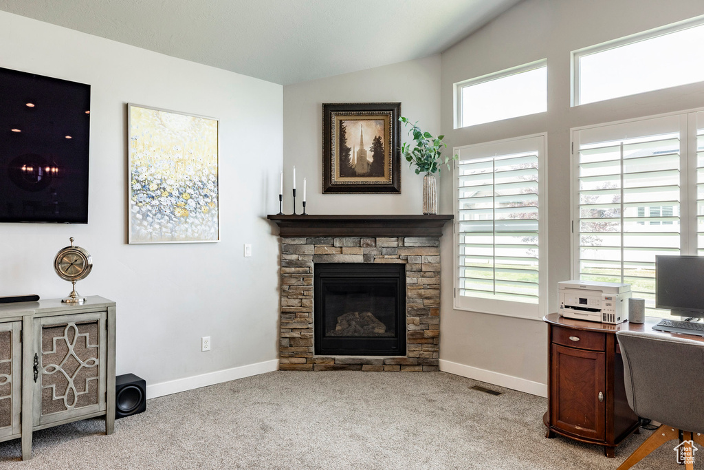 Office space with lofted ceiling, light colored carpet, and a stone fireplace