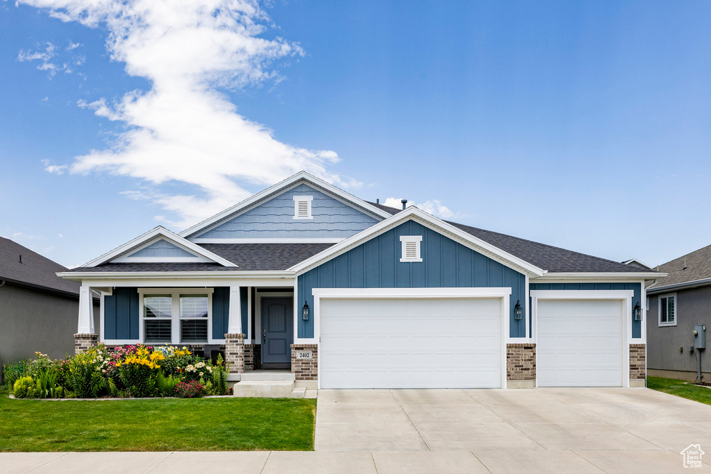 Craftsman inspired home with a garage, a front lawn, driveway, roof with shingles, and a porch