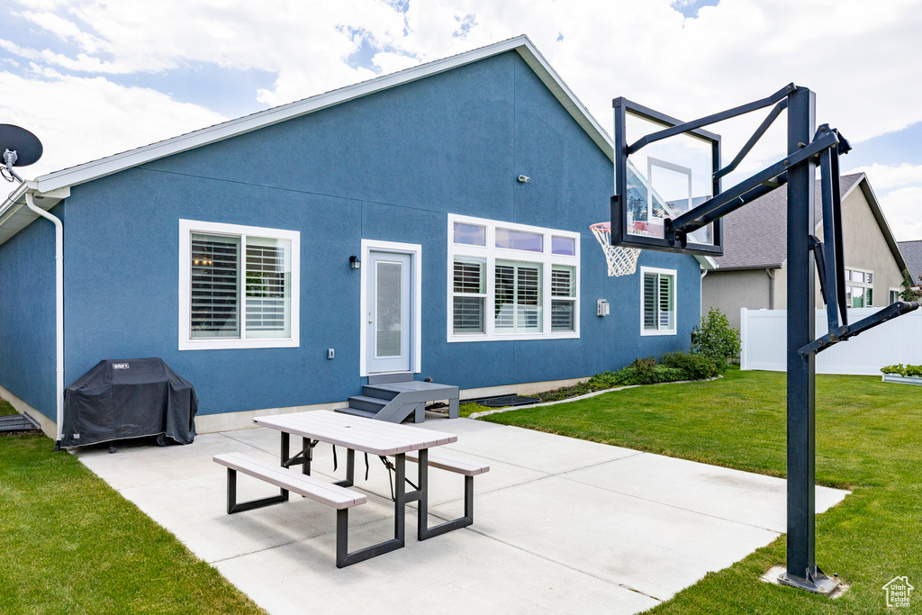 Back of house with a yard, stucco siding, and a patio area
