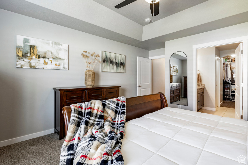 Bedroom with a ceiling fan, light colored carpet, and ensuite bath
