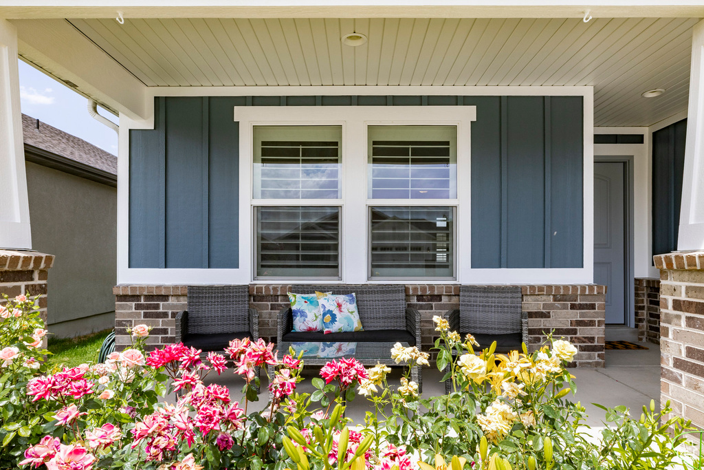 Property entrance with board and batten siding, a porch, brick siding, and stone siding
