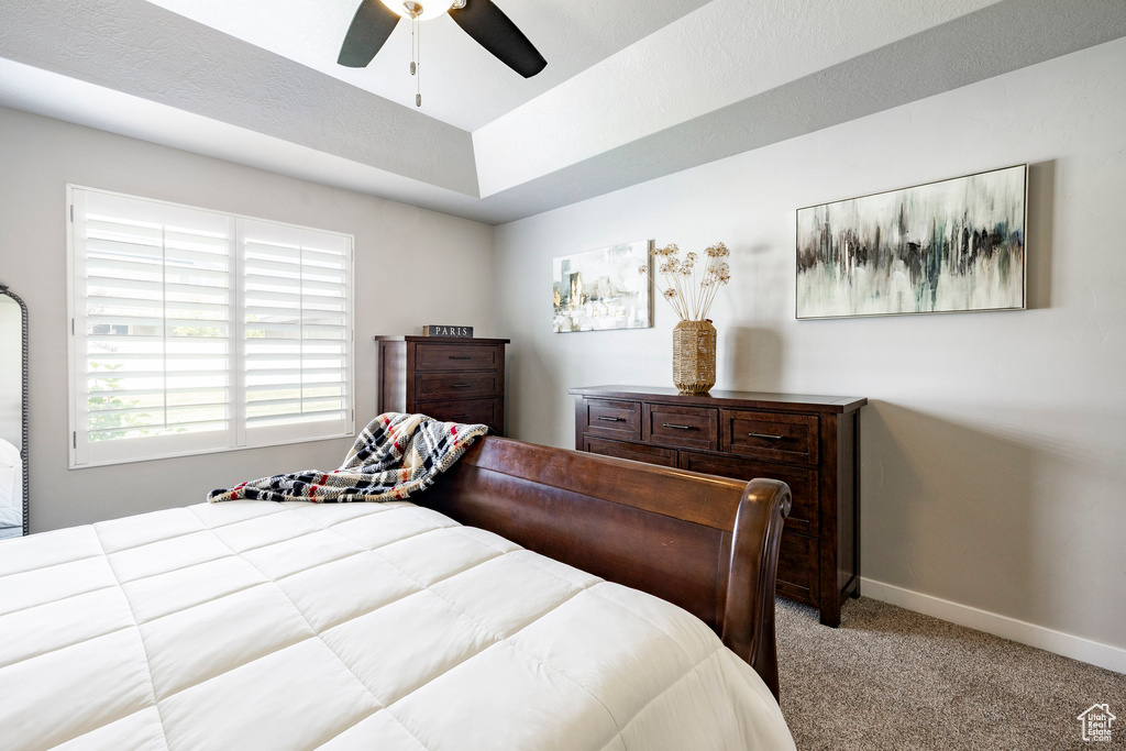 Bedroom featuring light colored carpet, a tray ceiling, and a ceiling fan
