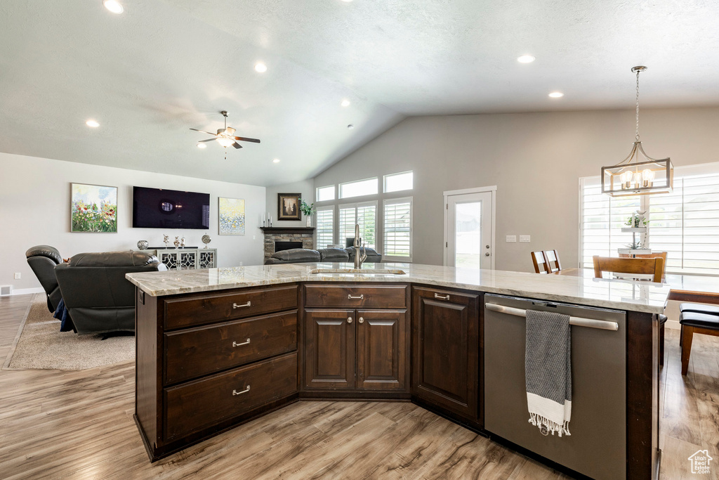 Kitchen featuring dishwasher, open floor plan, a chandelier, a fireplace, and vaulted ceiling