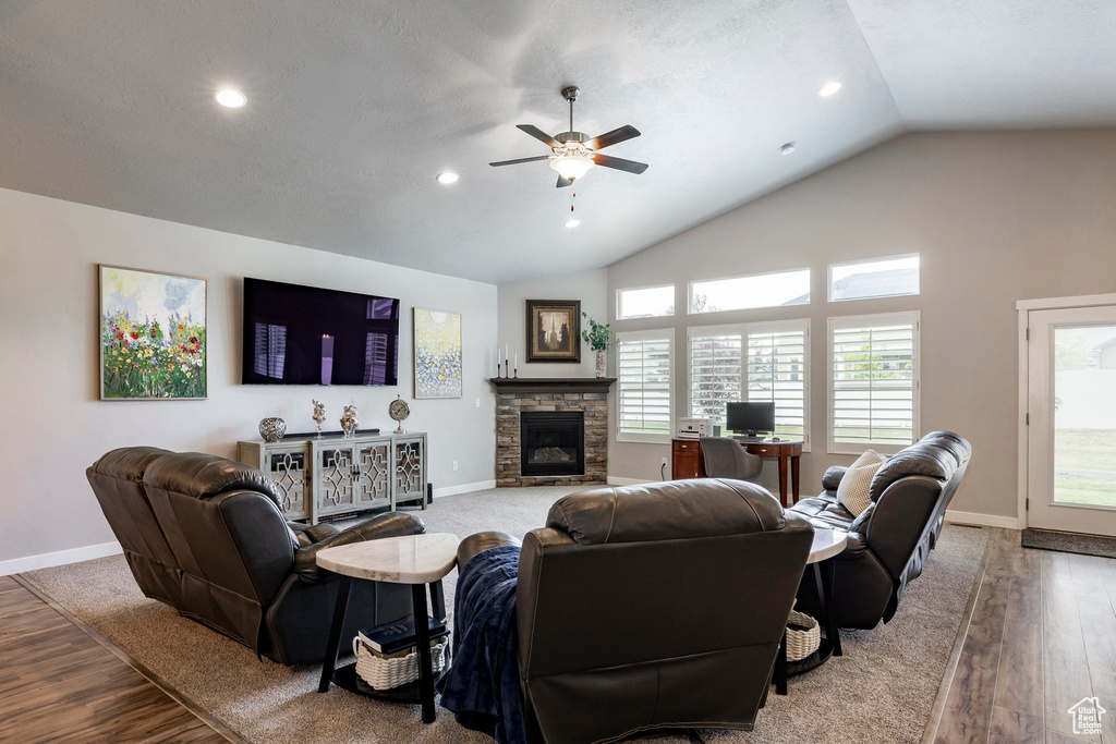 Living room featuring vaulted ceiling, ceiling fan, wood finished floors, a fireplace, and recessed lighting
