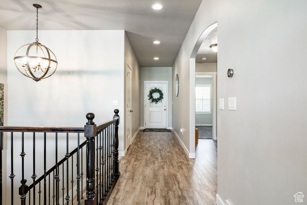 Hallway featuring a chandelier, light wood-style flooring, arched walkways, and recessed lighting