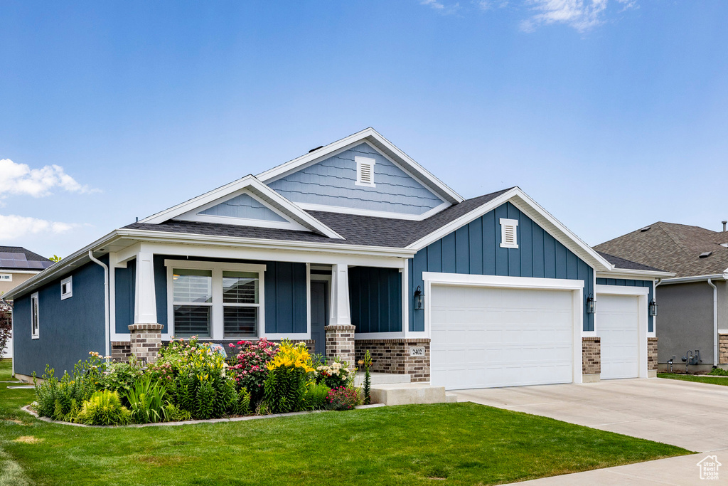 Craftsman-style house featuring an attached garage, a front lawn, concrete driveway, roof with shingles, and board and batten siding