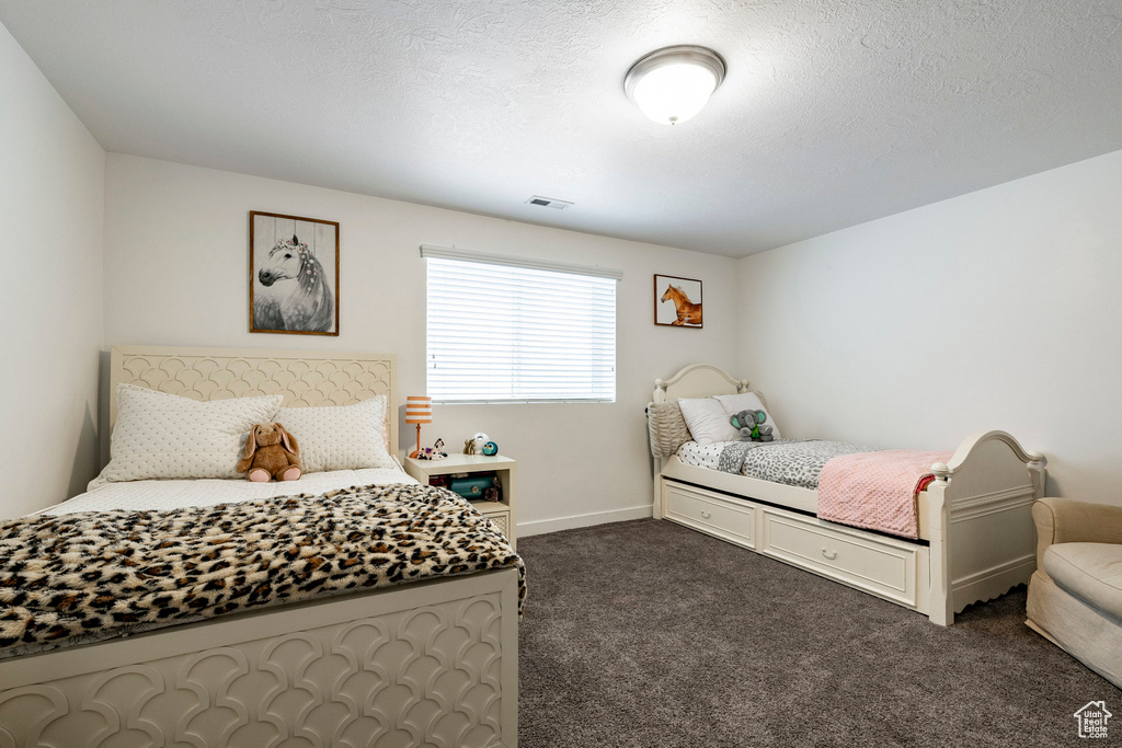 Bedroom with dark colored carpet and baseboards