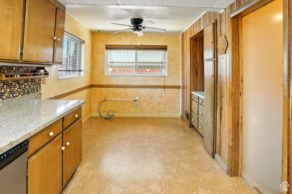 Kitchen with stainless steel dishwasher, ceiling fan, decorative backsplash, brown cabinets, and light flooring