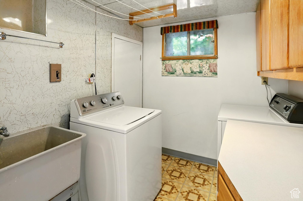 Laundry room with cabinet space, washing machine and dryer, and light flooring