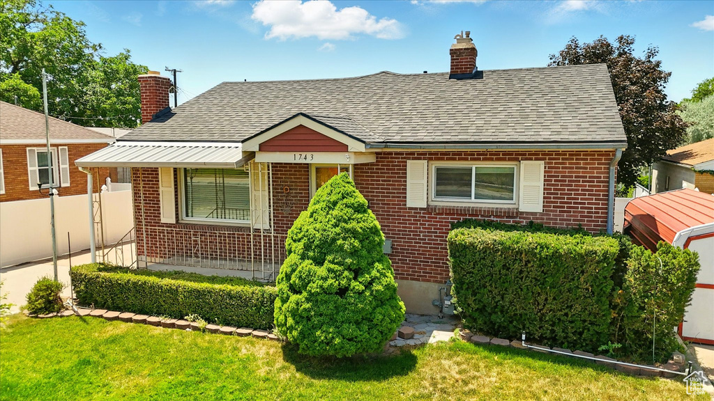 Bungalow featuring brick siding, a chimney, and roof with shingles